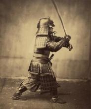 Sepia toned image of a man in samurai armor lunging forward with his sword raised