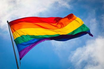 The pride flag fluttering in the breeze in front of a blue sky